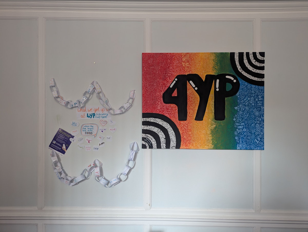 A wall display showing 4YP branding and youth-created artwork including paper chains and colorful posters